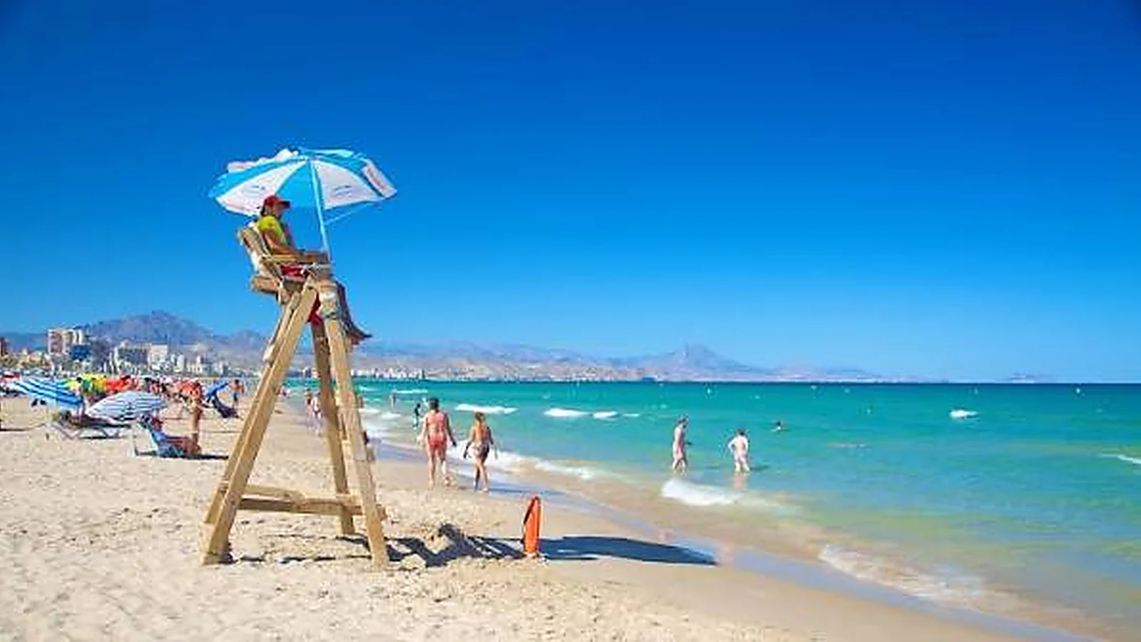 La playa de San Juan, con el puesto de socorrismo y la sierra al fondo