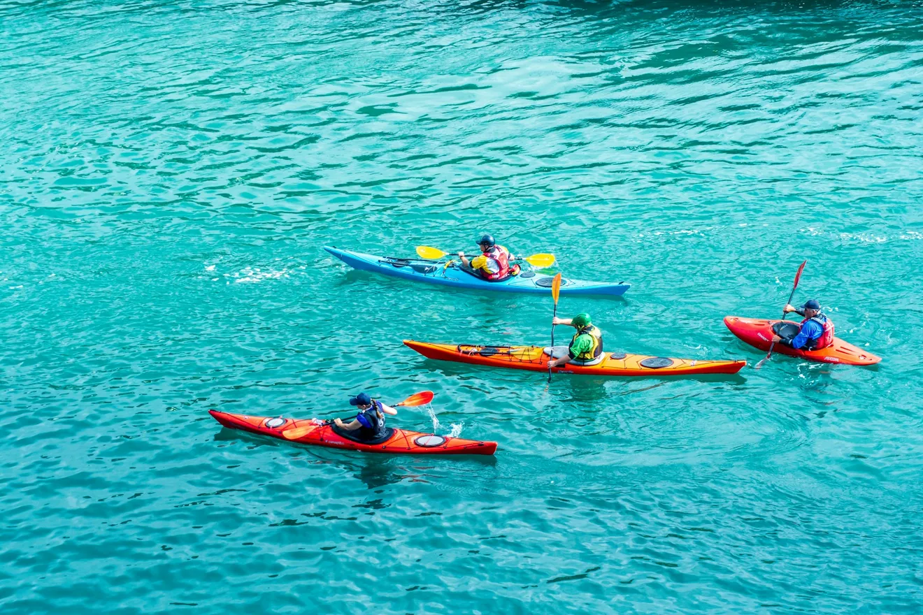Varios kayaks remando sobre agua turquesa